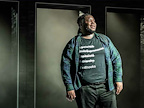 An actor in a green shirt looking to the side in A Strange Loop