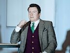 Man in suit sat at desk looking concerned