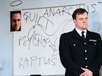 Man in uniform stood infront of whiteboard with the words Guilt, Anarchist and Raptus written on it.