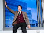 Man in suit and tie sat on a window ledge