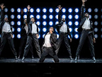 Four of the Temptations standing up, pointing upwards with one on their knees