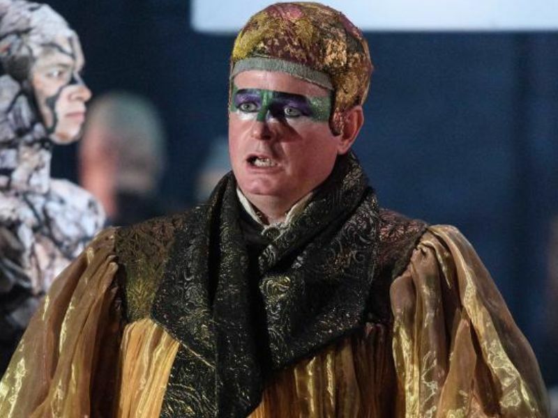 Image: Colin Judson stood on stage with mouth hanging open. He is wearing green eye makeup and golden robes.