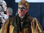 Image: Colin Judson stood on stage with mouth hanging open. He is wearing green eye makeup and golden robes.