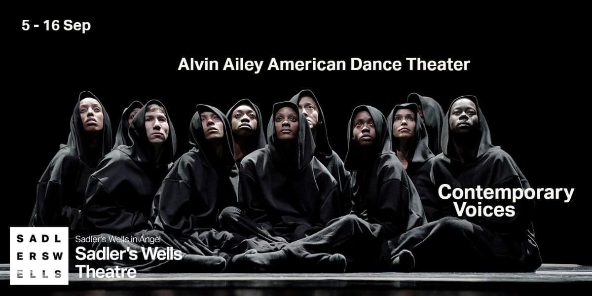 Text: Alvin Ailey American Dance Theater Contemporary Voices. Image: A group of dancers are sat with their legs crossed. They are dressed in black with hoods up. The background is black.