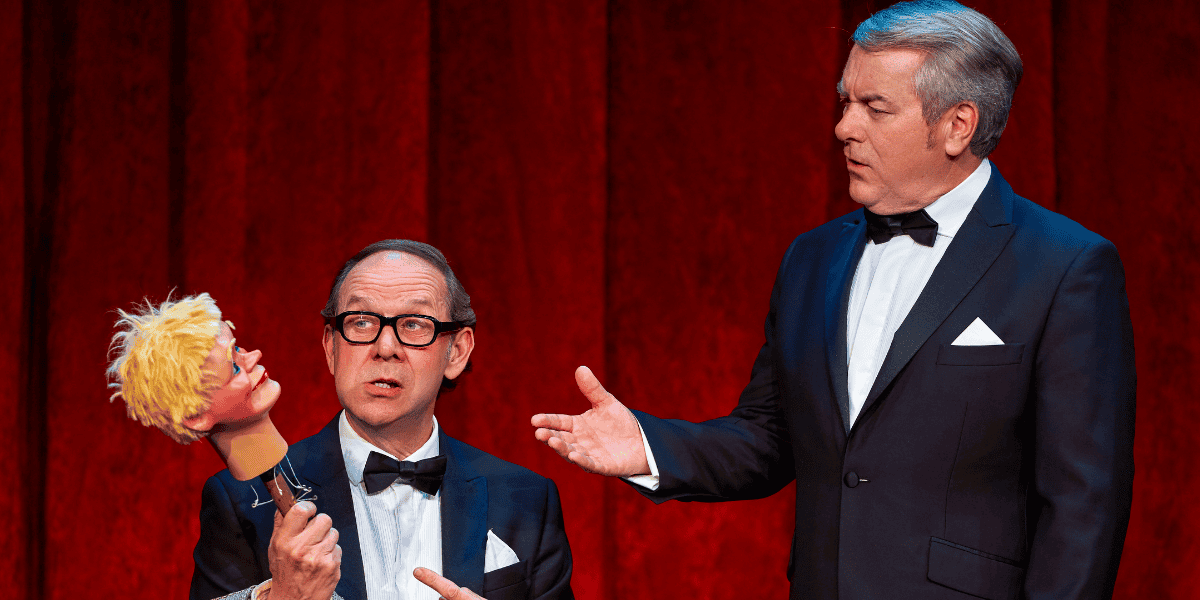 Two men in tuxedos with one holding a puppets head from An Evening of Eric and Ern. 