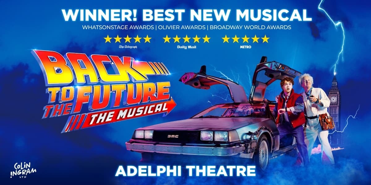 TEXT: Back to the Future the Musical. Adelphi theatre. Doc and Marty stand next to the Delorean time machine which has both doors open. Doc looks at a stop watch, Marty at his wrist watch. The city clock tower is in the background.