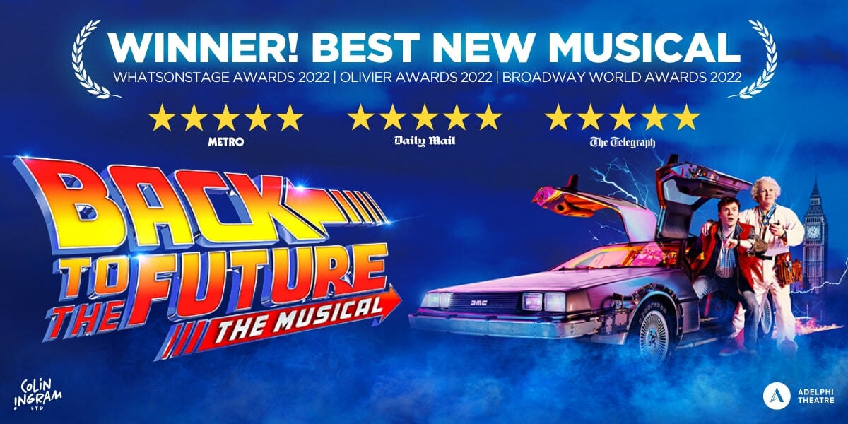 TEXT: Winner! Best New Musical. Back to the Future the Musical. Adelphi theatre. Doc and Marty stand next to the Delorean time machine which has both doors open. Doc looks at a stop watch, Marty at his wrist watch. The city clock tower is in the background.