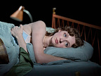 Woman lying on her side in bed with her eyes open.