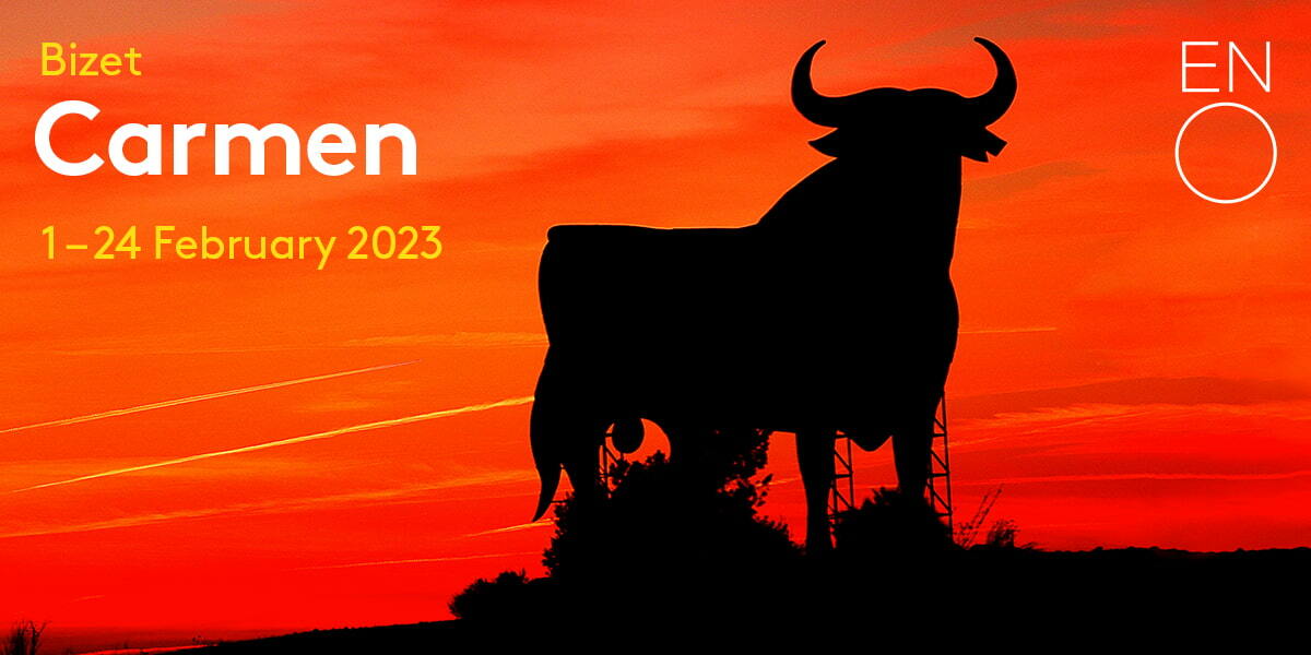 Bizet Carmen 1 February - 24 February 2023 ENO. A gigantic billboard of a bull is silhouetted against a red and orange sunset.