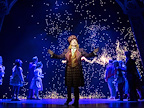 Willy Wonka stood in front of a group of children whilst stars explode behind them.