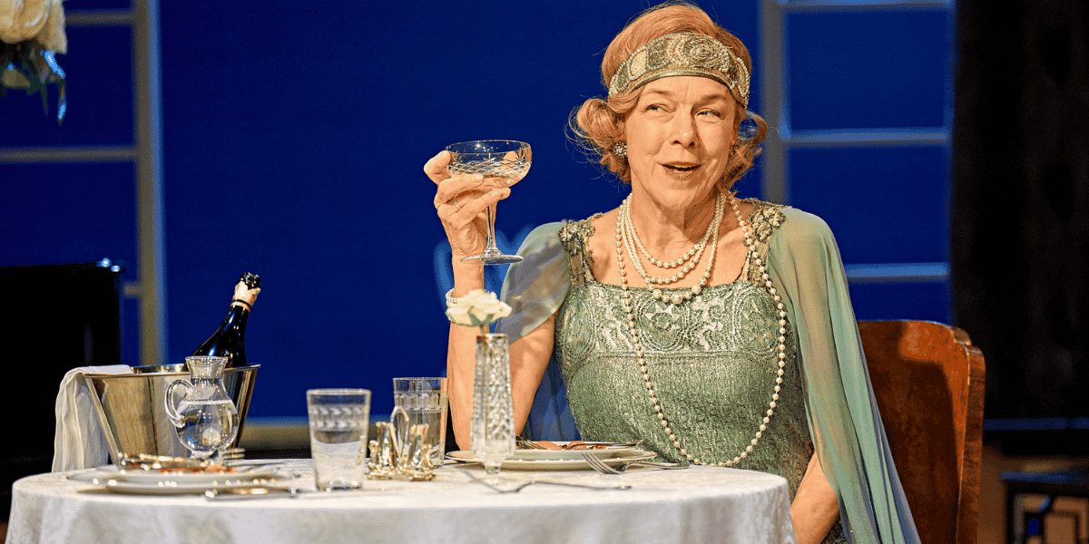 Woman in green dress raising a glass at the table from Fallen Angels 
