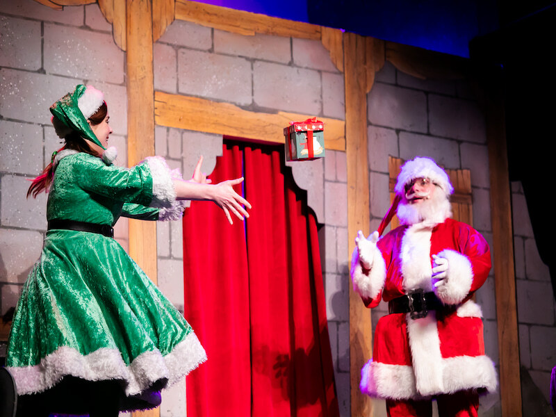 Woman in green reaching out to Father Christmas