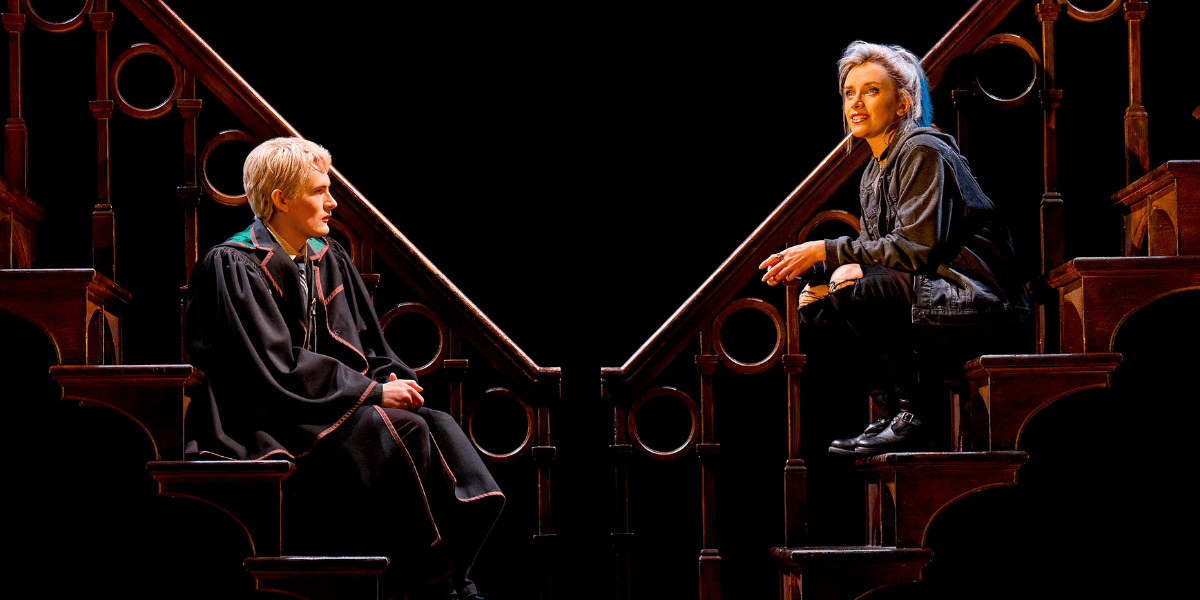 Image: Two Hogwarts students seated on the stairs, talking together Show: Harry Potter and the Cursed Child