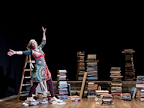 Danyah Miller on a stage surrounded by piles of books and a step ladder.