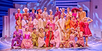 The cast of MAMMA MIA! are dressed in pink and orange wedding outfits