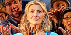 Donna and the cast of MAMMA MIA! are stood next to each other, looking up to the camera with hands extended