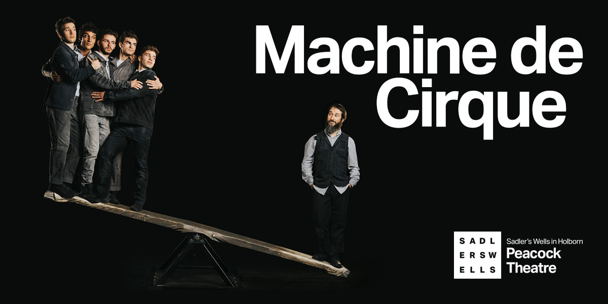 A puzzle for physics: six men stand on a seesaw. To the left, a group of five men in their twenties, wearing jeans and casual jackets in shades of grey. They cling to each other, looking suspiciously over towards the sixth man. He has a thick beard and a knowing smile, as he stands with hands in his pockets, holding down his end of the seesaw alone. TEXT: Machine de Cirque [SADLERS WELLS LOGO] Peacock Theatre