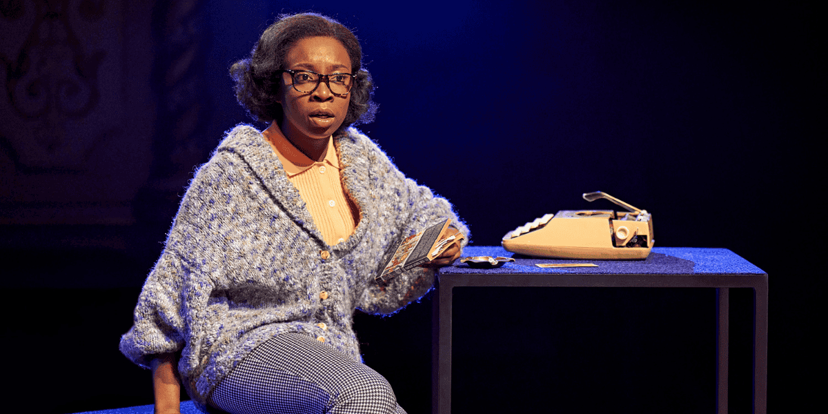 Woman sitting down on a table with a typewriter in Mary Page Marlowe
