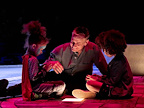 Man sat on floor with face illuminated with two children