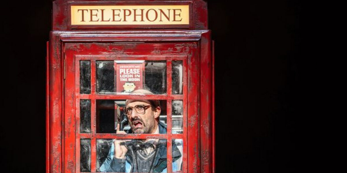 Red London telephone box with confused man inside in the West End stage production.
