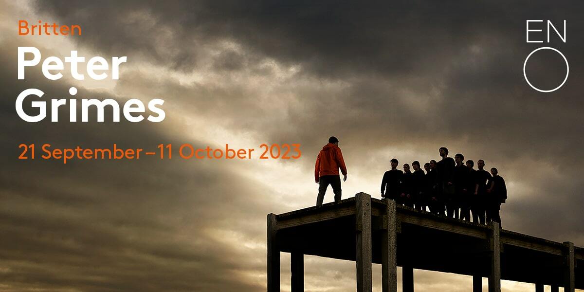 Text: Britten Peter Grimes 21 September - 11 October 2023. Image: A crowd of people stood at the end of a pier confronting a man on his own wearing a red jacket.
