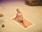 Sheridan Smith in Shirley Valentine - reclining on beach towel on beach, sunglasses on head, wearing tshirt and denim shorts.
