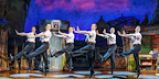 A group of missionaries in white shirts and ties perform a lively dance number in the Book of Mormon musical.