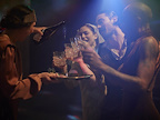 One woman pouring drinks for another woman and two men, into cut glass tumblers.