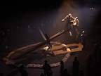 A man and woman stood on a giant girder whilst surrounded by onlookers.
