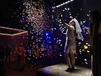 A woman wearing a bridal head veil looking upwards as confetti rains down.