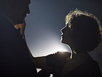 Backlit woman touching mans face