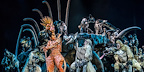 Scar stands among the hyenas in a dramatic, darkly lit scene from The Lion King musical.