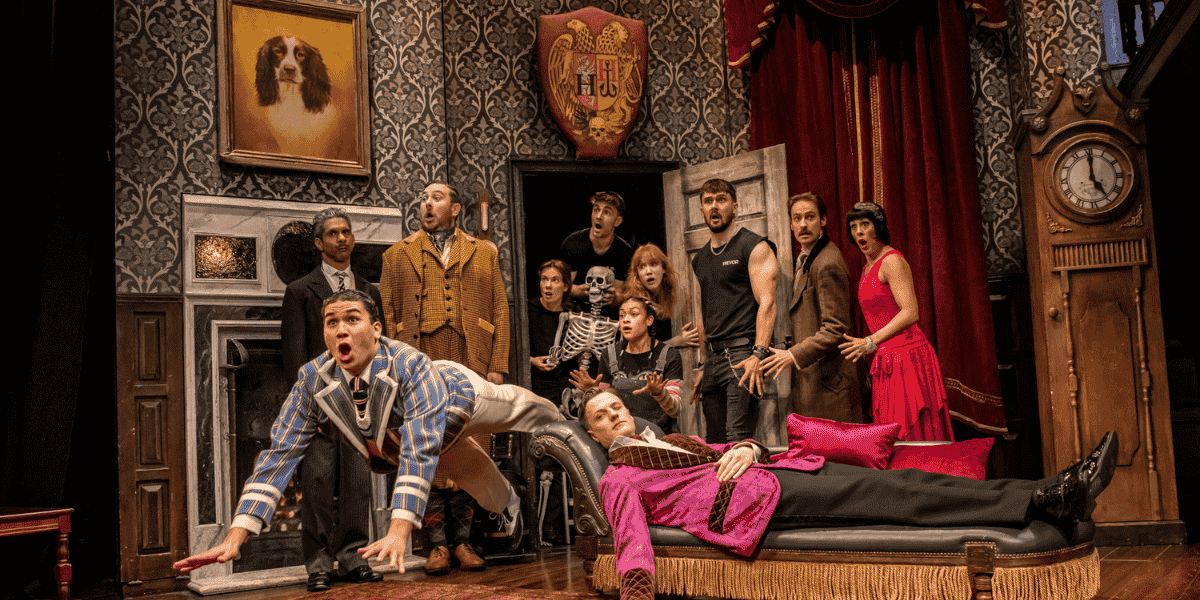 Group of people looking shocked and man falling in The Play That Goes Wrong