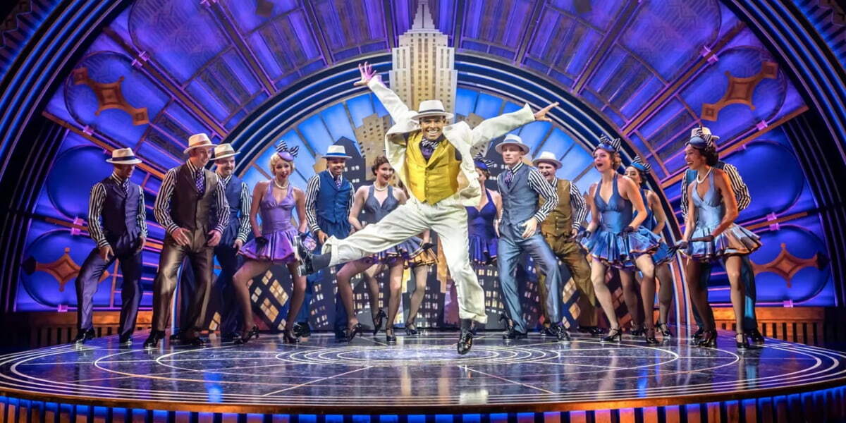 Dancers perform a glamorous 1930s routine in Top Hat, with a lead performer leaping centre stage in a white suit.