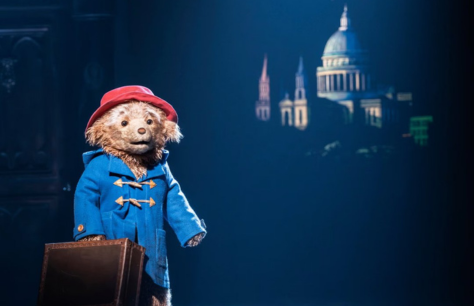 Paddington the bear stares into the audience as the Brown family gather around him on stage