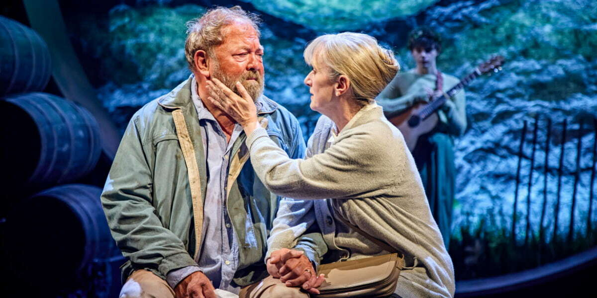 Mark Addy and Jenna Russell in The Unlikely Pilgrimage of Harold Fry, with Russell gently touching Addy’s face as they share an emotional moment on stage,