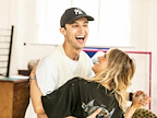 Two people are joyfully laughing and embracing in a bright, indoor space. They appear to be enjoying each other's company.
