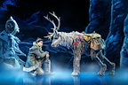 A character interacts with a reindeer in a snowy, theatrical setting. The scene conveys a sense of adventure.