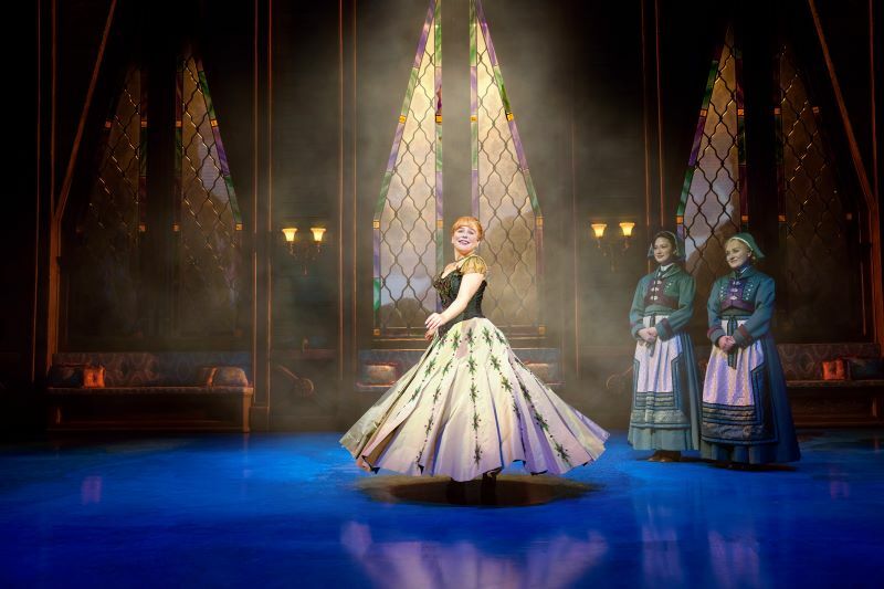 (L to R) Emily Lane (Anna), Isabella Glanznig Santos (Handmaiden_Ensemble), Rebecca Botterill (Handmaiden_Ensemble)- Disney's Frozen the Musical - Photo by Johan Persson © Disney