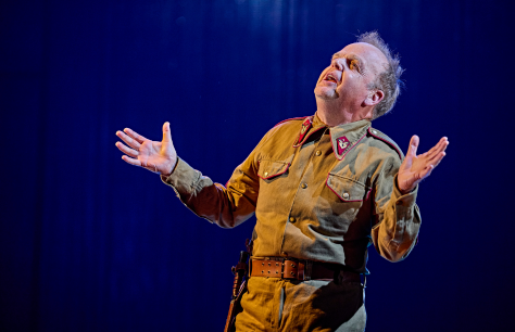 Toby Jones as Iago in Othello throws his head back in evil laughter dressed in a military uniform